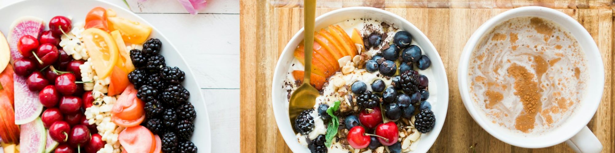 The image shows a healthy breakfast with bowls of yogurt and fresh fruits, a cup of coffee, an avocado, and some flowers on a white table.